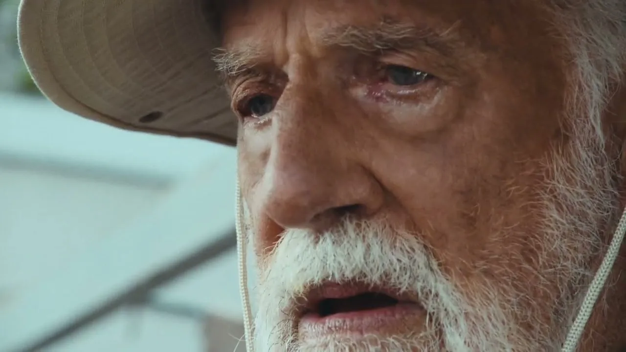 Jonathan Goldsmith in 2026, close up under a wide brimmed hat, white beard, looking off camera